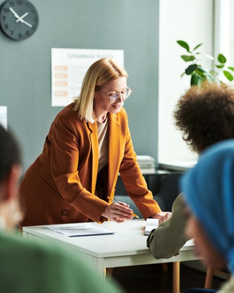 Confident Blond Mature Teacher Explaining Something to Student